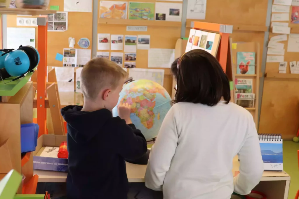 deux enfants de dos qui regardent un globe terrestre